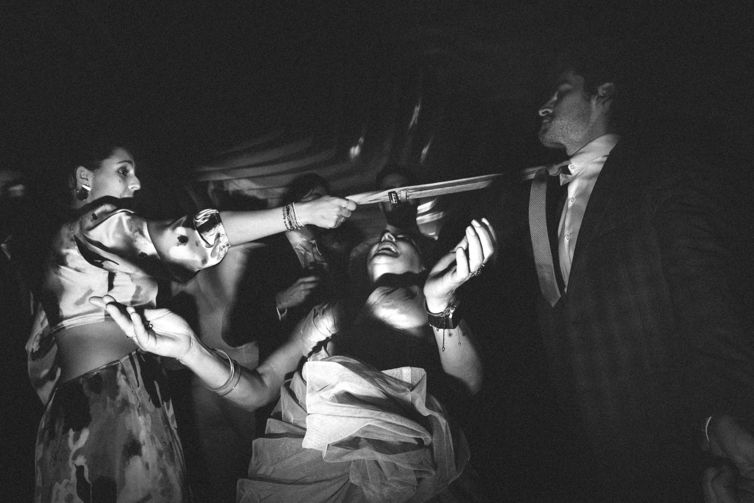 Dark concert scene with silhouettes of people moshing and crowd surfing at a punk show.