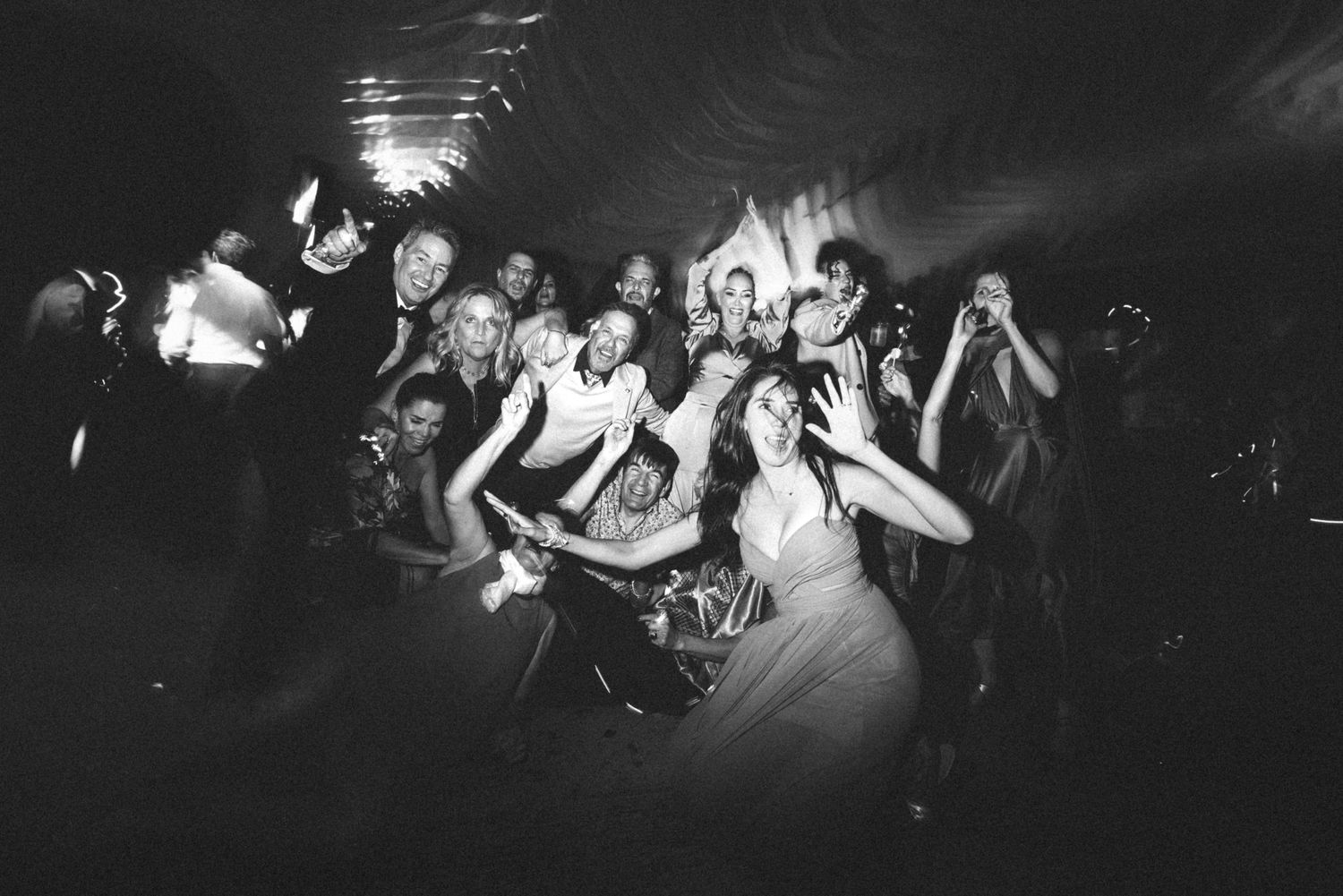 Wide angle shot of a dimly lit concert venue with crowd silhouettes and stage lighting.