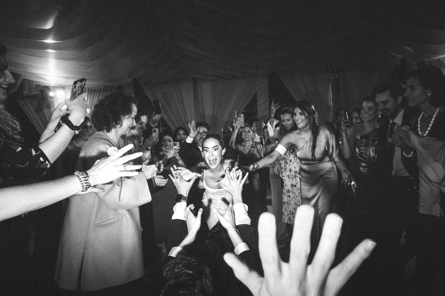 Wedding guests dance and celebrate on a dark dance floor illuminated by dramatic lighting effects.