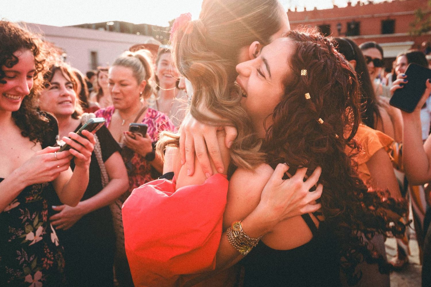 Wedding celebration with people dancing and embracing at an outdoor reception.