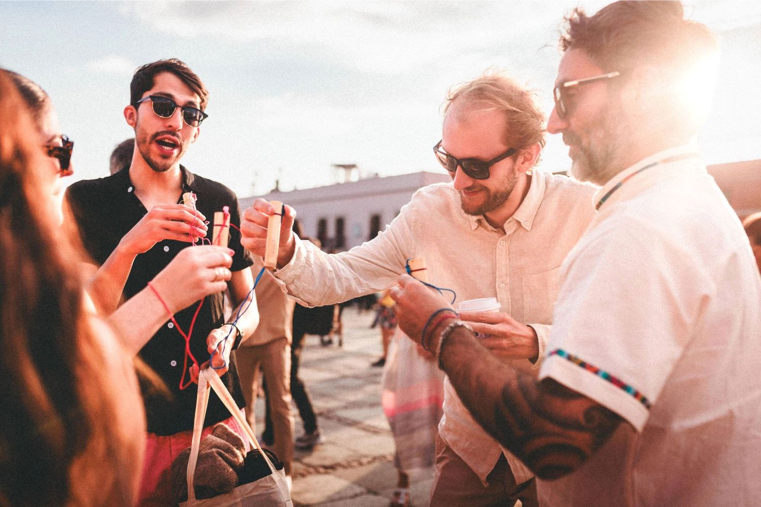 Group of friends enjoying drinks together outdoors during golden hour sunset.