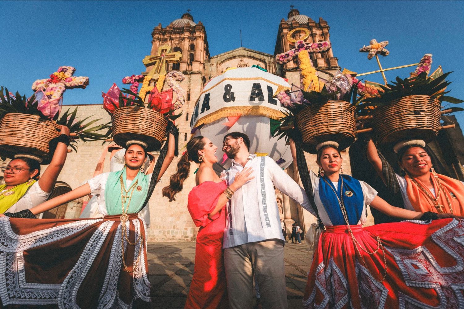 Panoramic view of a lively outdoor festival crowd with colorful clothing and raised arms.