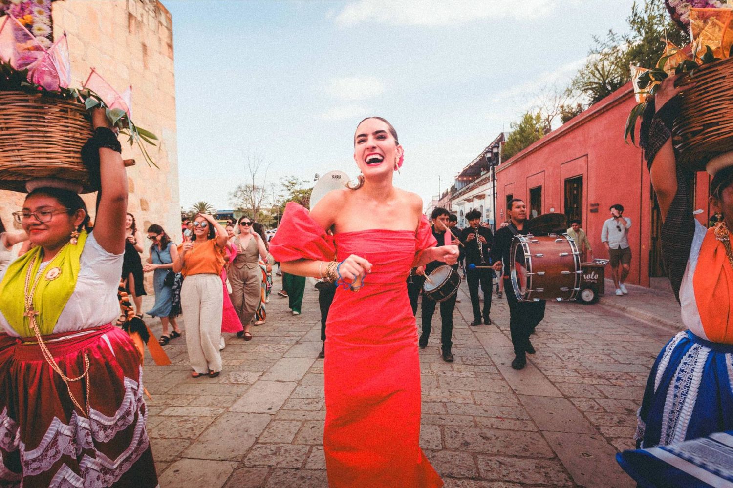 People walking and gathering along a historic red-walled street during a festive celebration.