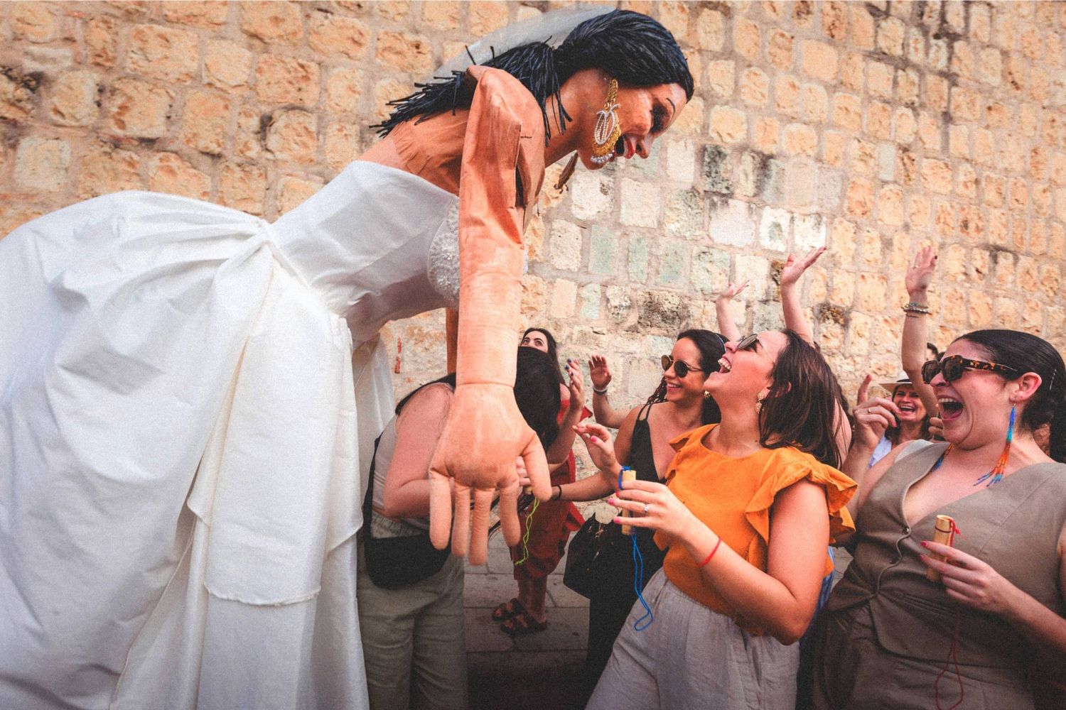A series of connected photos showing people dancing and celebrating against a rustic stone wall background.