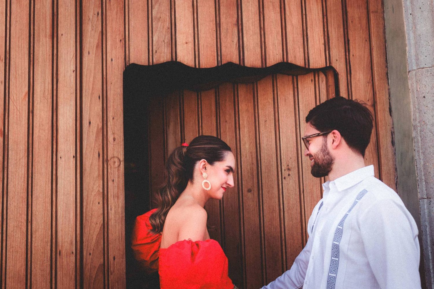 Couple sharing a romantic moment against a rustic wooden wall backdrop.