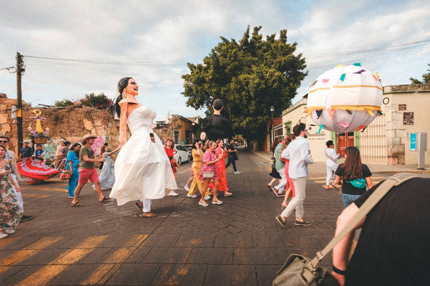 Wedding party dancing and celebrating outdoors during sunset with string lights overhead.