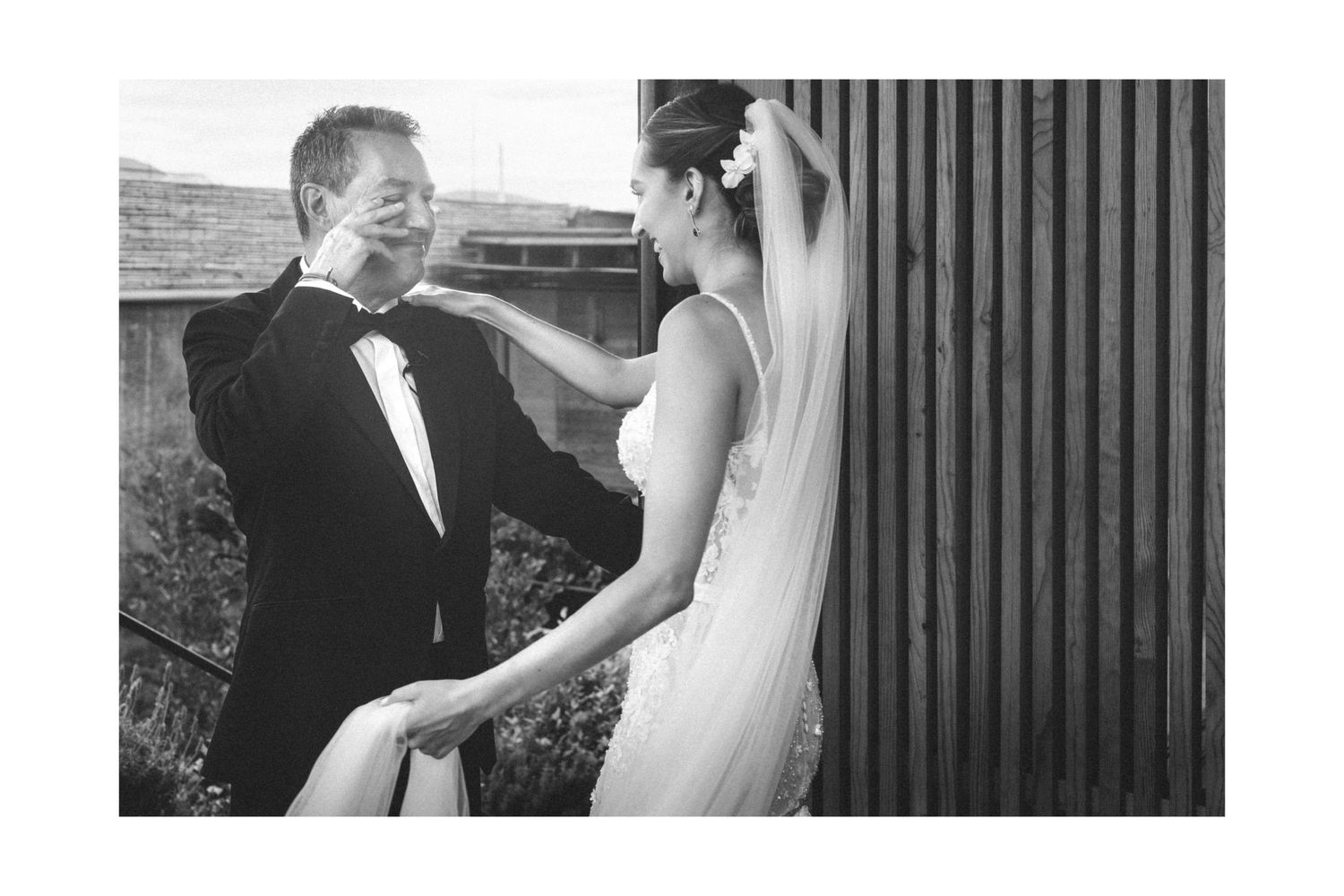 Elegant black and white wedding photo showing a couple sharing an intimate moment outdoors.