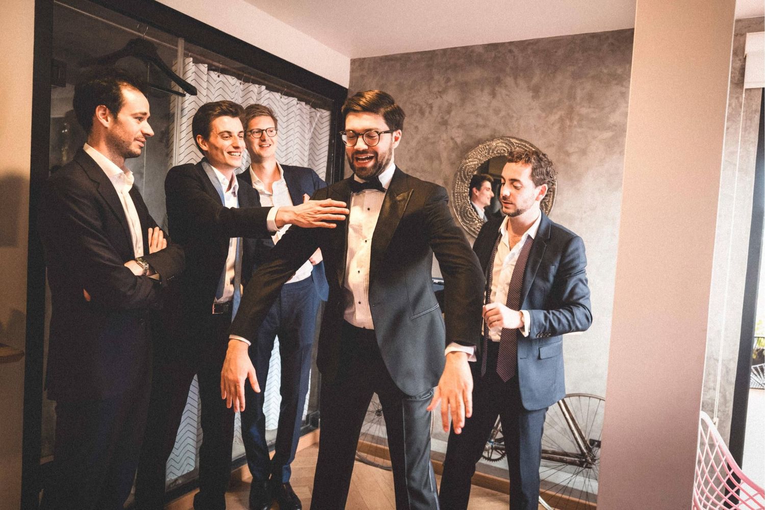 Group of formally dressed people posing together against an industrial style wall.