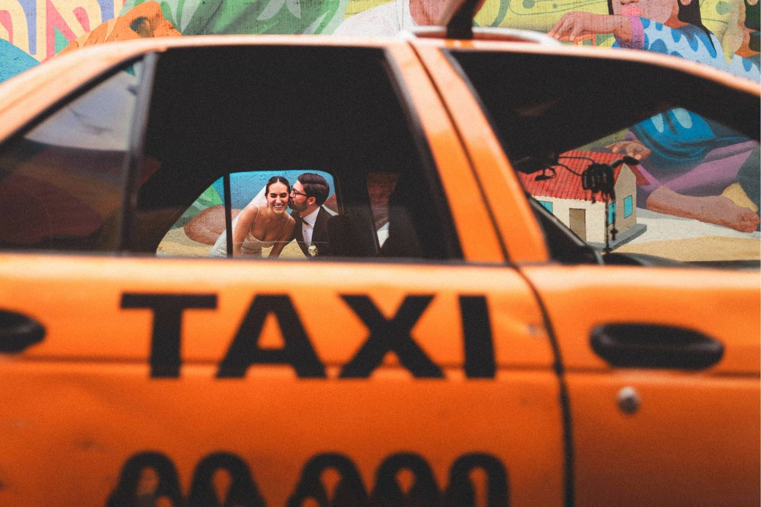 A row of bright orange taxi cabs lined up on a city street during daytime.