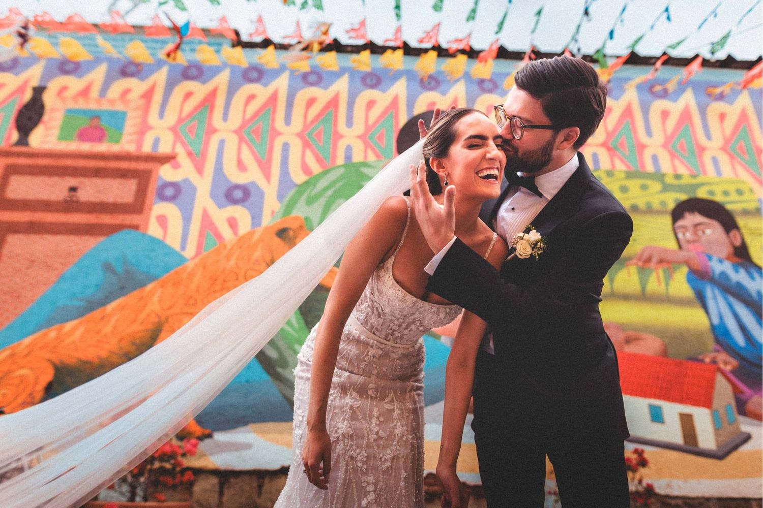 A couple dances and embraces on an outdoor dance floor decorated with colorful flags and banners.