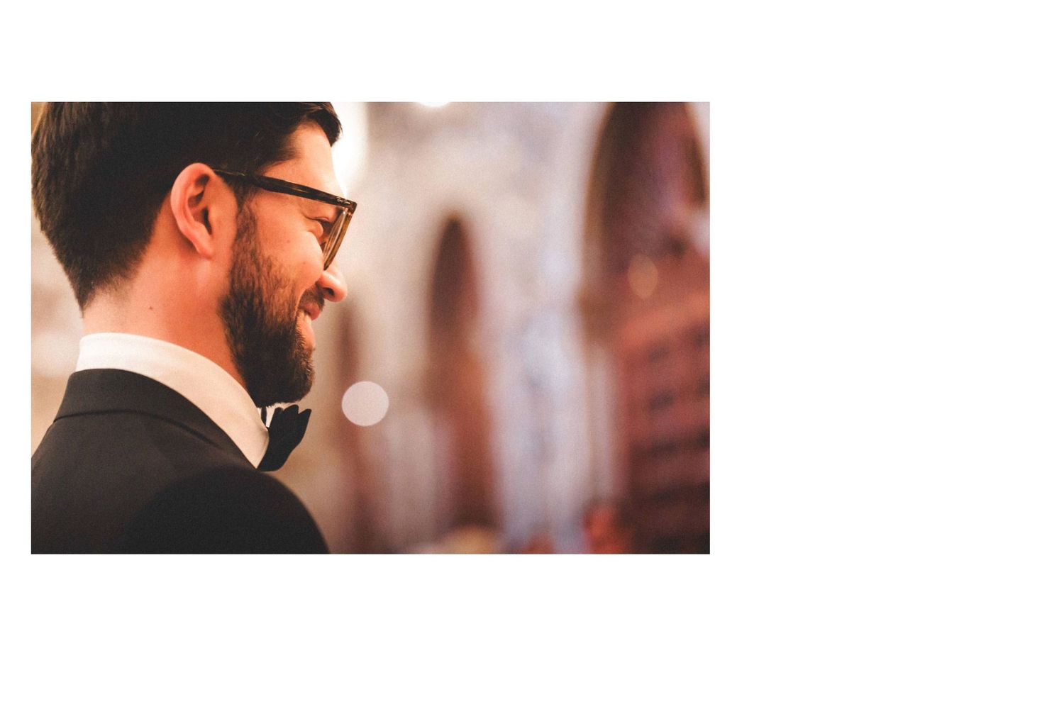 Close-up side profile view of someone wearing glasses and a black suit at an elegant event.
