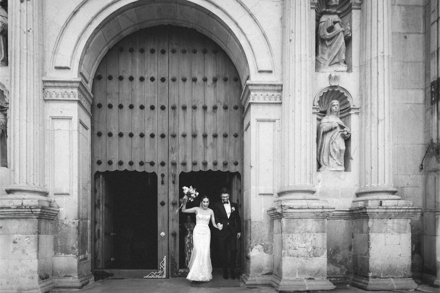 Historic stone church exterior with arched doorways and white architectural details in black and white photography.