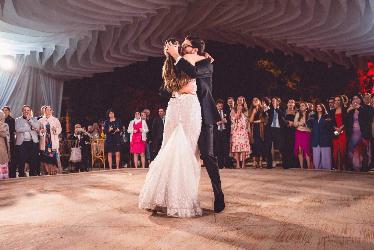 Couples dancing together at an elegant wedding reception on a wooden dance floor surrounded by guests.