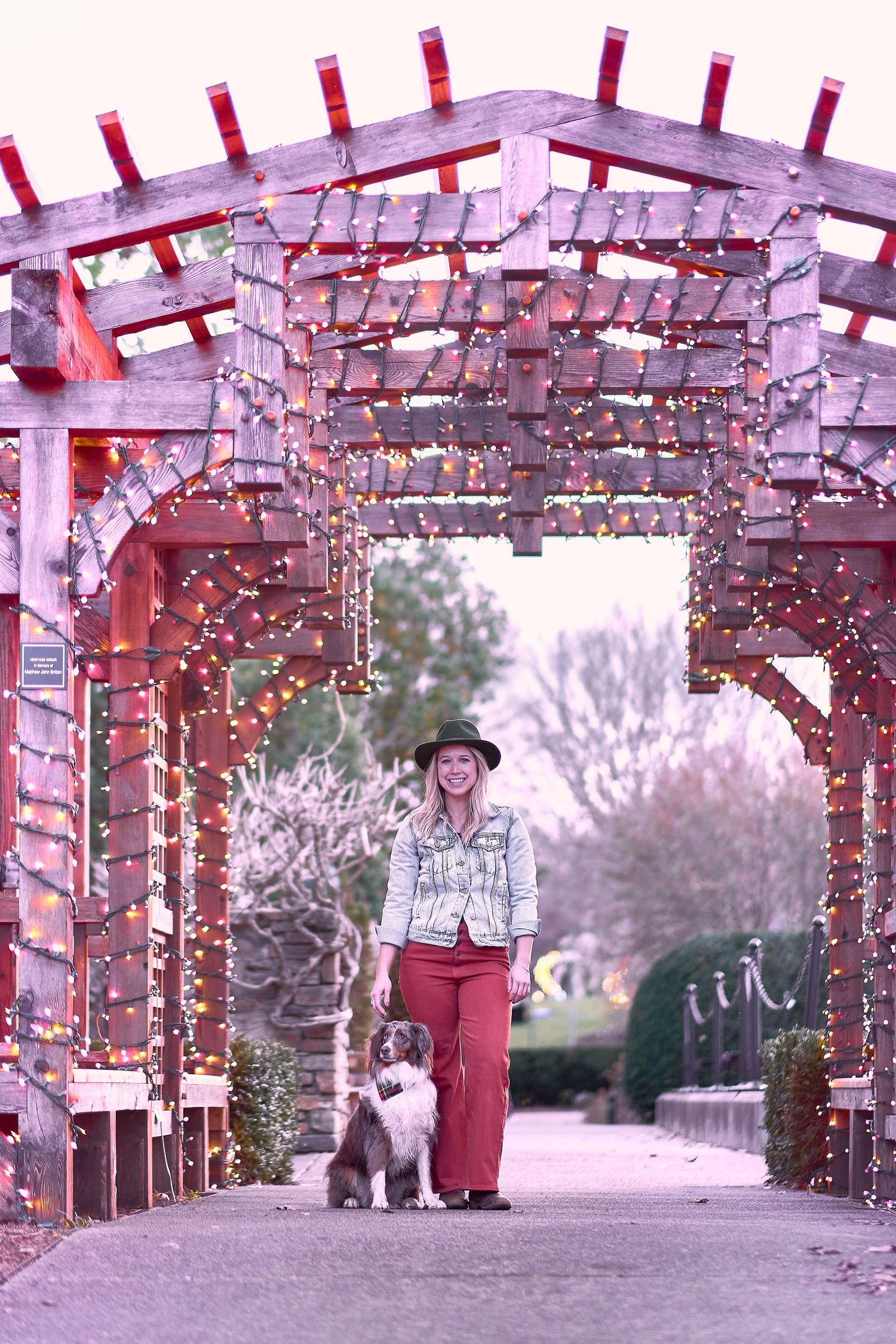String lights illuminate a wooden pergola decorated for a festive outdoor celebration at dusk.