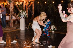 People dancing and celebrating at a dimly lit outdoor wedding reception with string lights overhead.