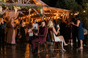 People dancing and celebrating at a rustic outdoor wedding venue illuminated by warm string lights at night.