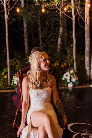 A couple shares a joyful moment during their outdoor wedding reception surrounded by trees and string lights.