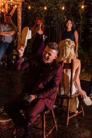 A joyful wedding reception moment captured outdoors with string lights and wooden chairs.