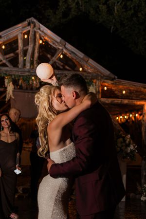 A romantic wedding dance under twinkling lights in a rustic wooden pavilion.