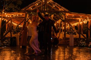 A rustic barn wedding reception venue illuminated with warm string lights creating a romantic evening atmosphere.
