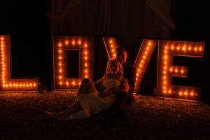 Decorative marquee letters spelling LOVE lit up in warm light against a dark outdoor background.