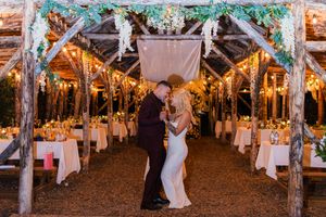 Rustic outdoor wedding reception venue decorated with string lights and white fabric creating a romantic ambiance.