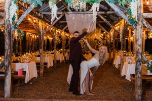 Wedding reception guests dancing and celebrating in a rustic barn venue decorated with string lights.