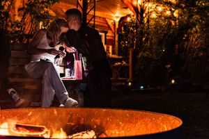 A glowing orange fire pit illuminates a nighttime outdoor gathering space with warm ambient lighting.