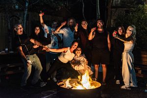 People gather around a fire pit at night performing acrobatic dance moves in a series of connected action shots.
