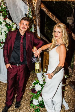 A couple poses together at a rustic wedding venue decorated with white flowers and draped fabric.
