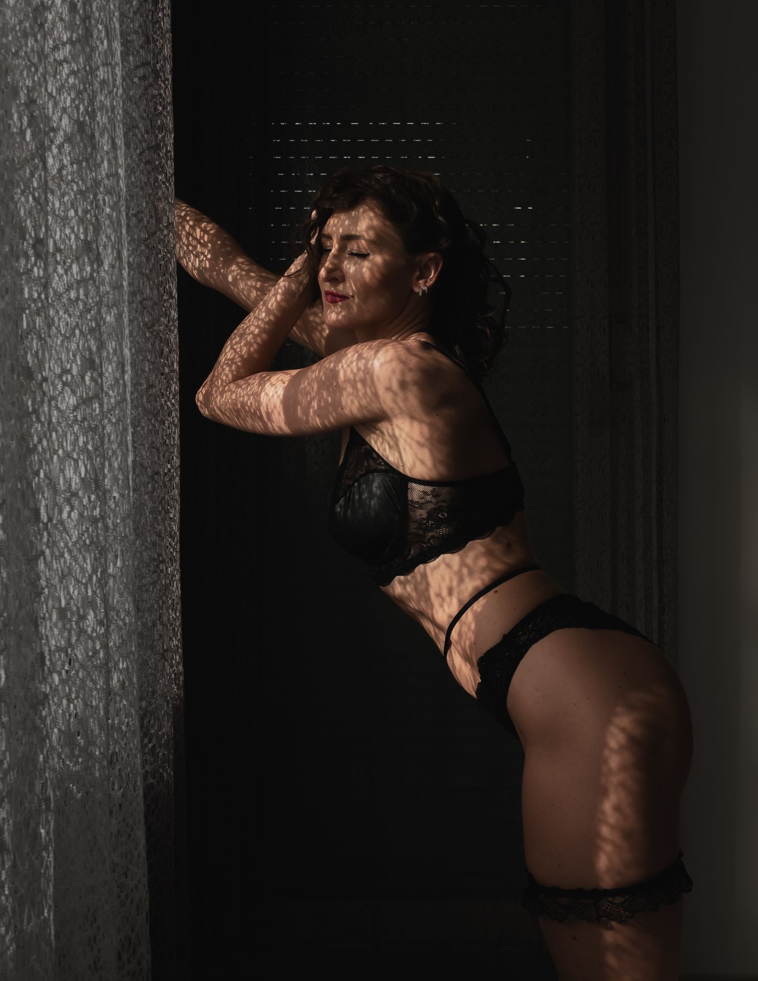 Umjetnička boudoir fotografija sa sjenama postavljena preko figure u crnom donjem rublju