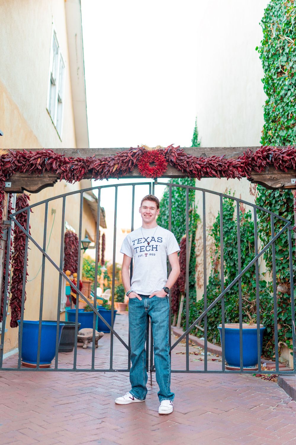 Person in Texas Tech shirt poses under archway decorated with red vines and greenery.