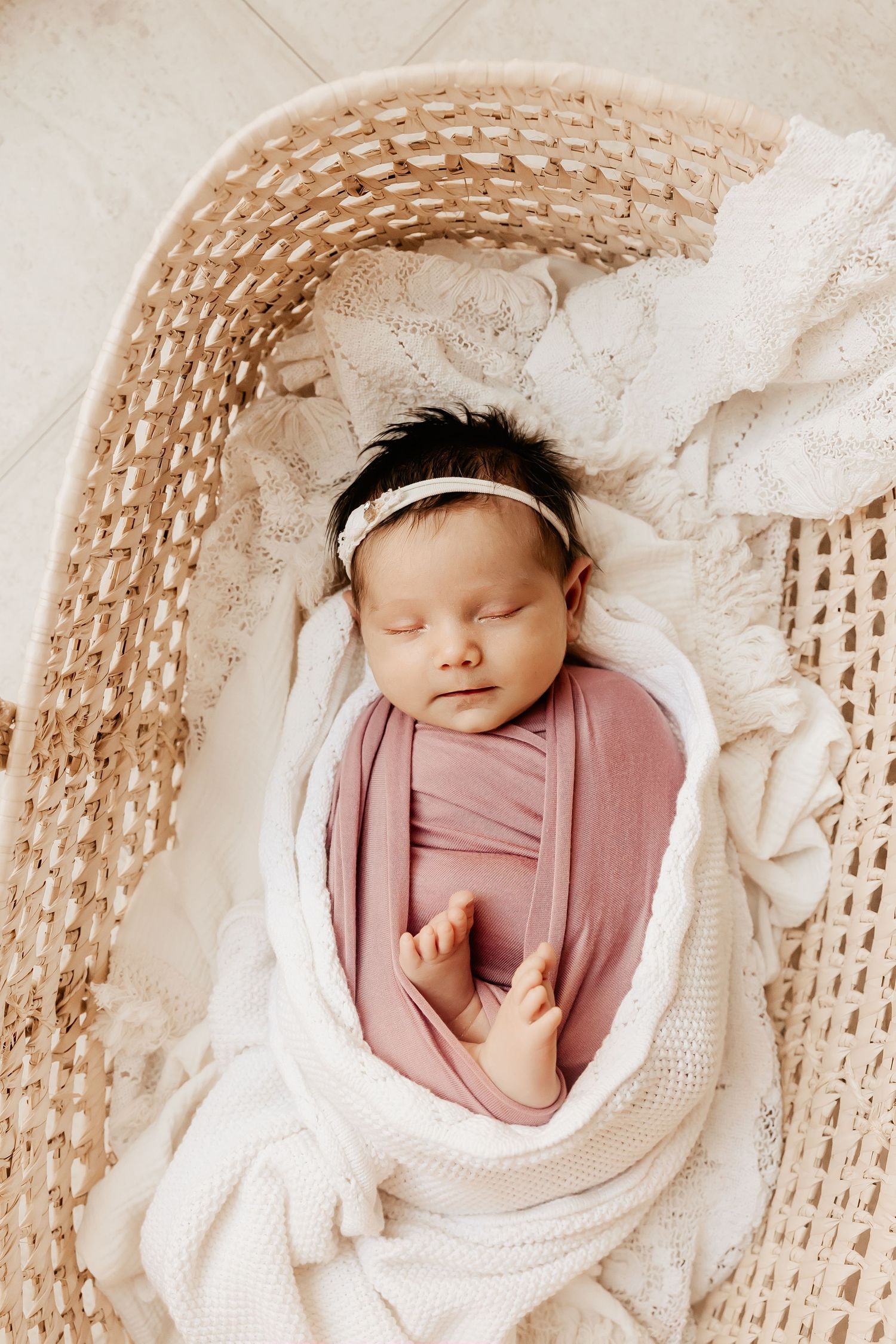 A newborn baby sleeps in a Moses basket during a Honolulu Newborn Photography session.