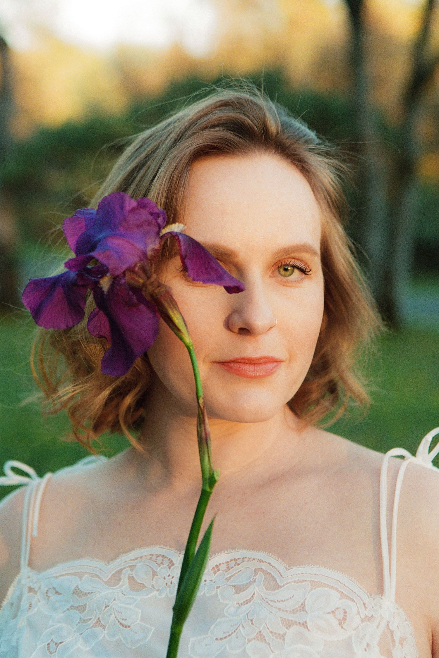 Purple iris flower held against white lace in soft natural lighting.