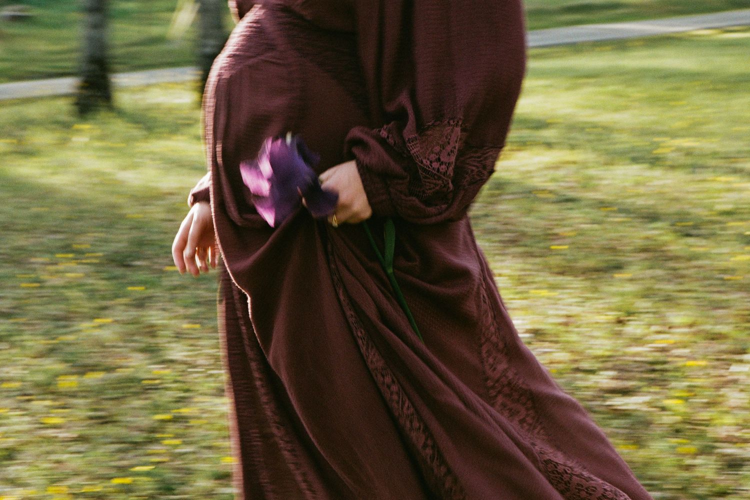 A flowing brown dress twirls gracefully in a sunlit outdoor setting.