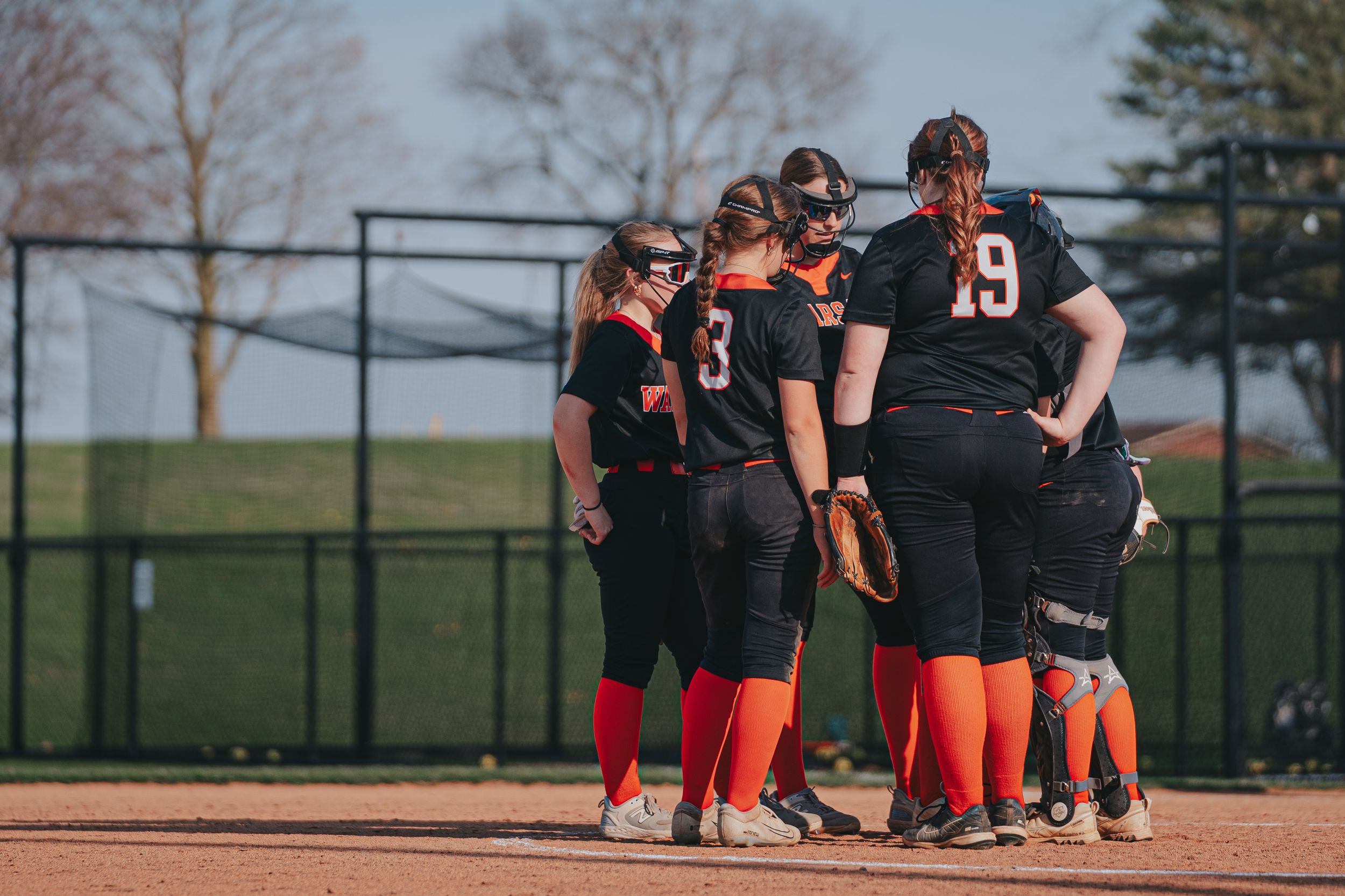 Sports Photography of a softball team huddling together on the field during a game - Warsaw, Indiana