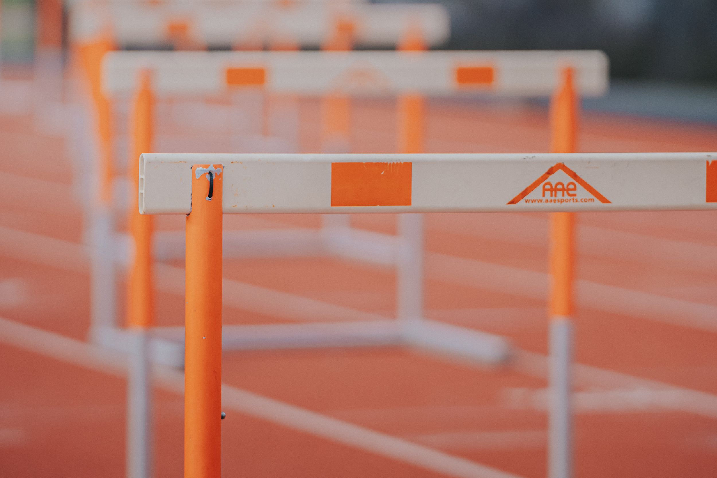 Sports Photography of orange and white track hurdles lined up on a running track - Warsaw, Indiana