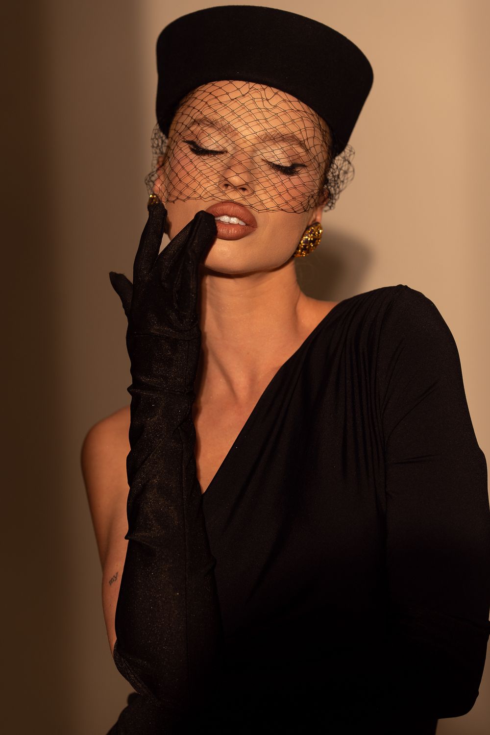 Fashion photograph featuring a model in black veil and gloves with classic vintage Hollywood glamour styling.
