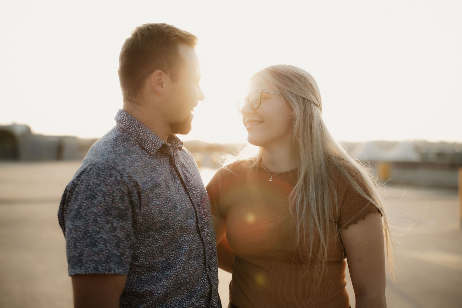 A backlit couple sharing a joyful moment during golden hour.