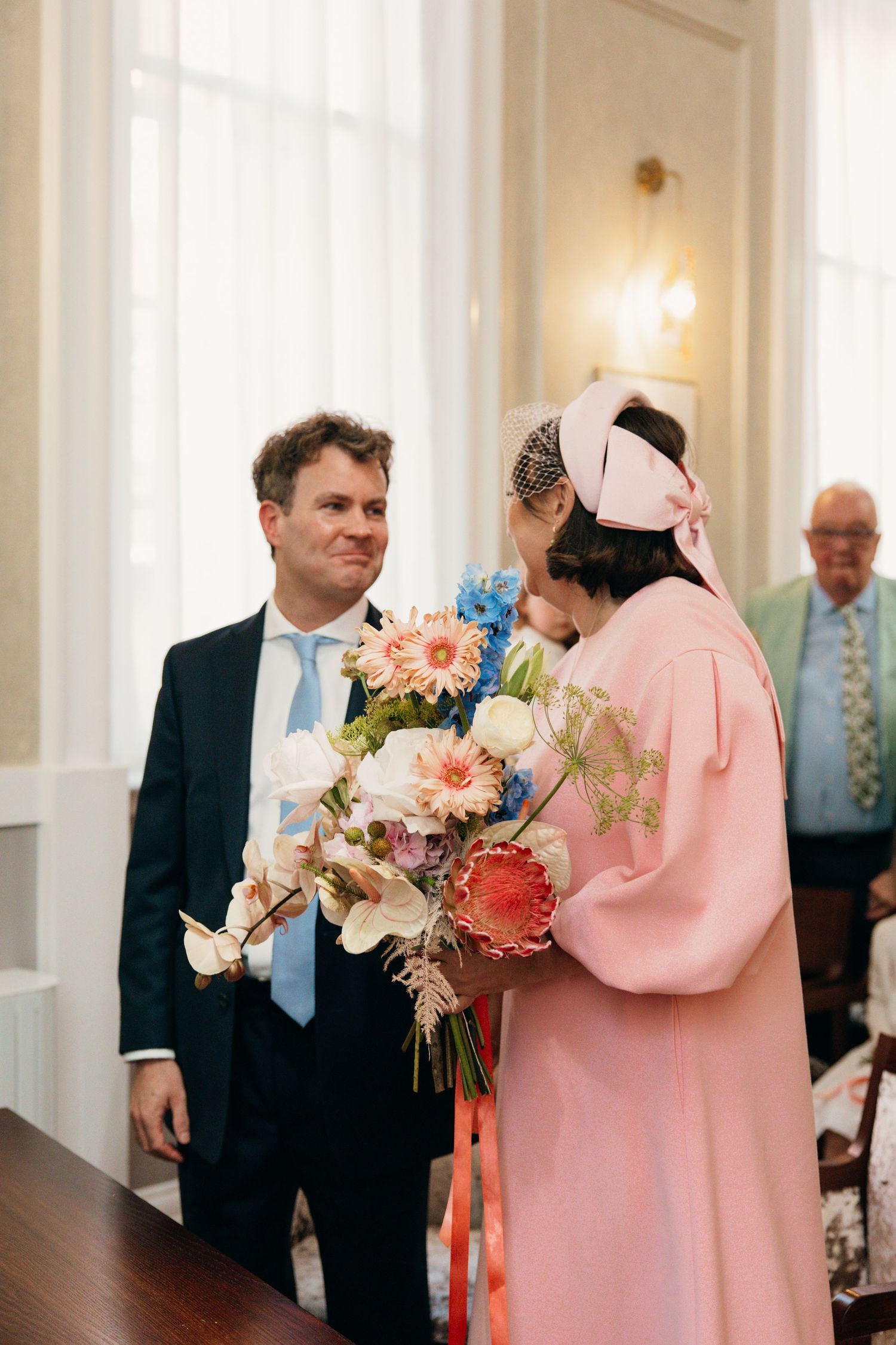A couple at a wedding ceremony exchanging flowers with pink and peach colored blooms.