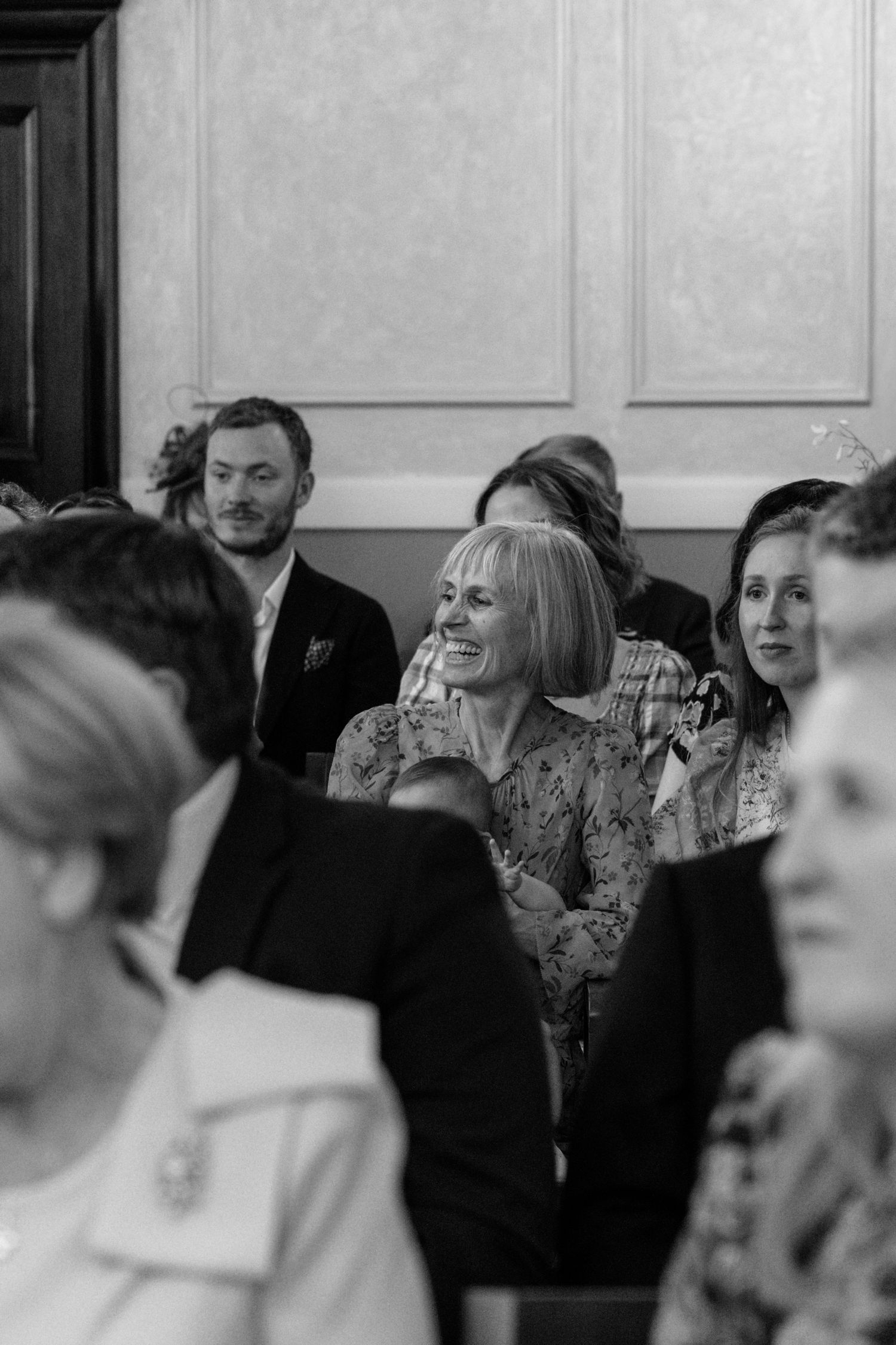 Black and white photo of wedding guests enjoying themselves during the ceremony.