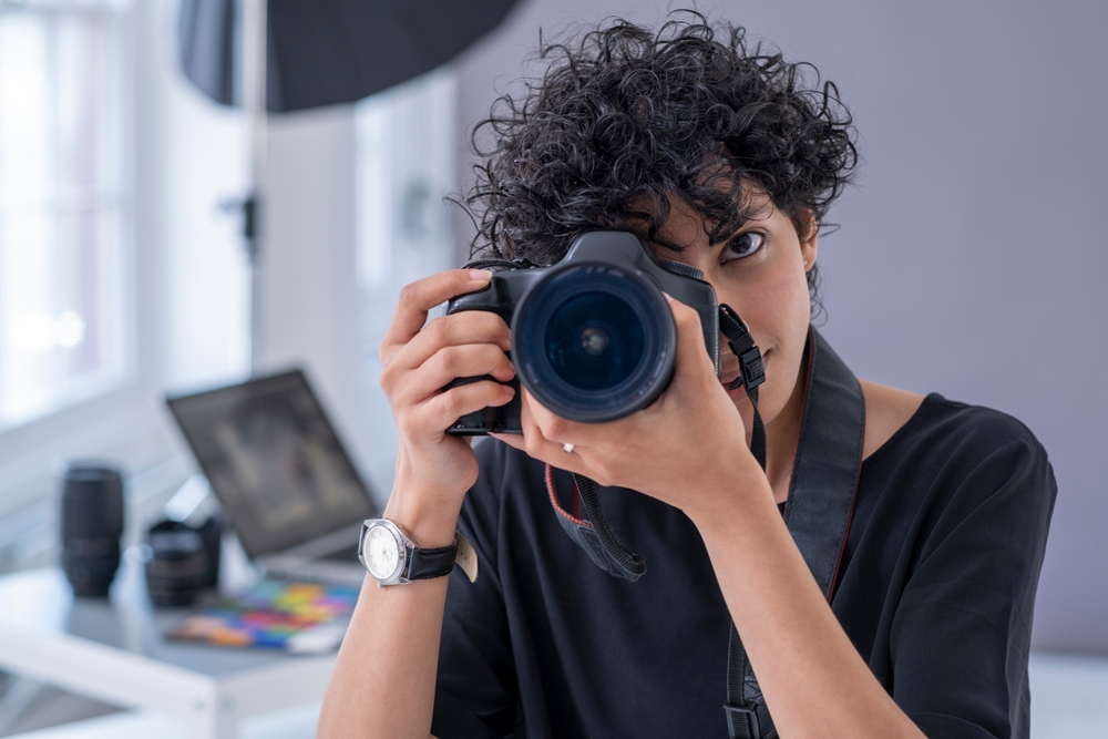 A photographer takes pictures with a professional DSLR camera in a bright studio setting.