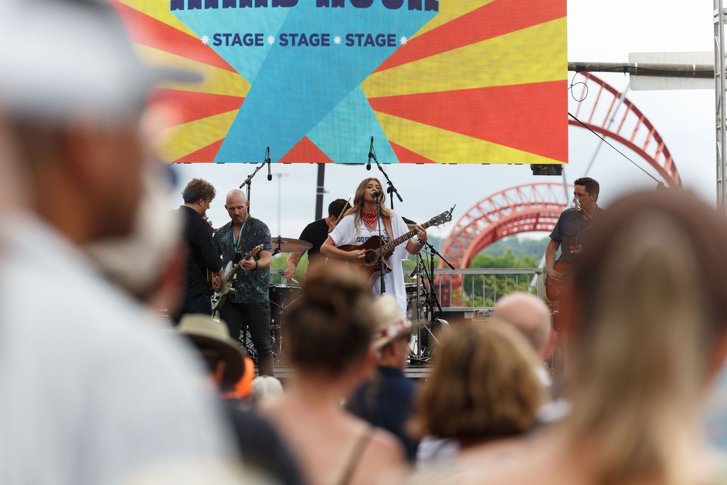 Live outdoor music performance at CMA Fest by Brennley Brown with colorful backdrop and crowd at festival stage.