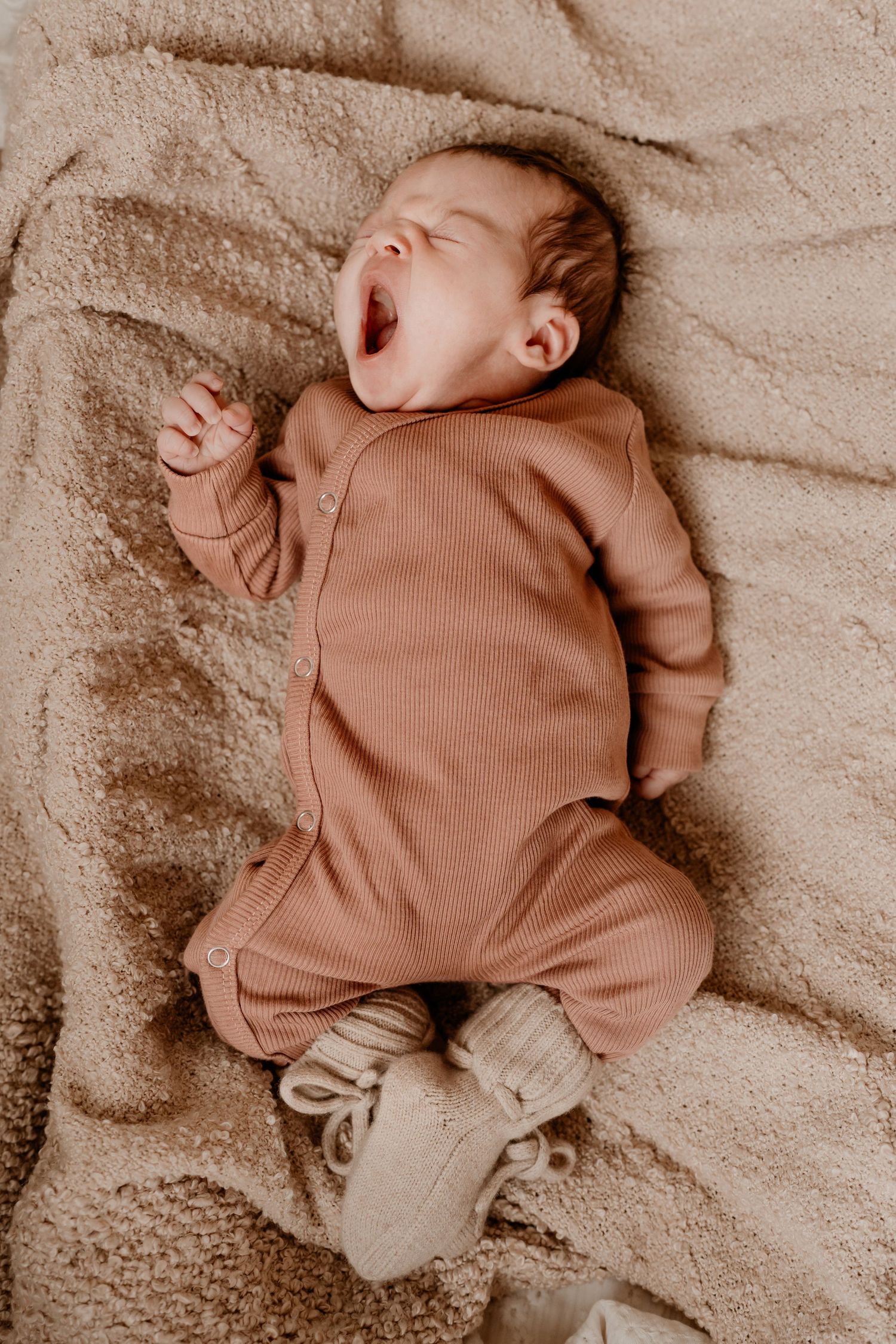 Een baby die aan het gapen is tijdens een newbornshoot.