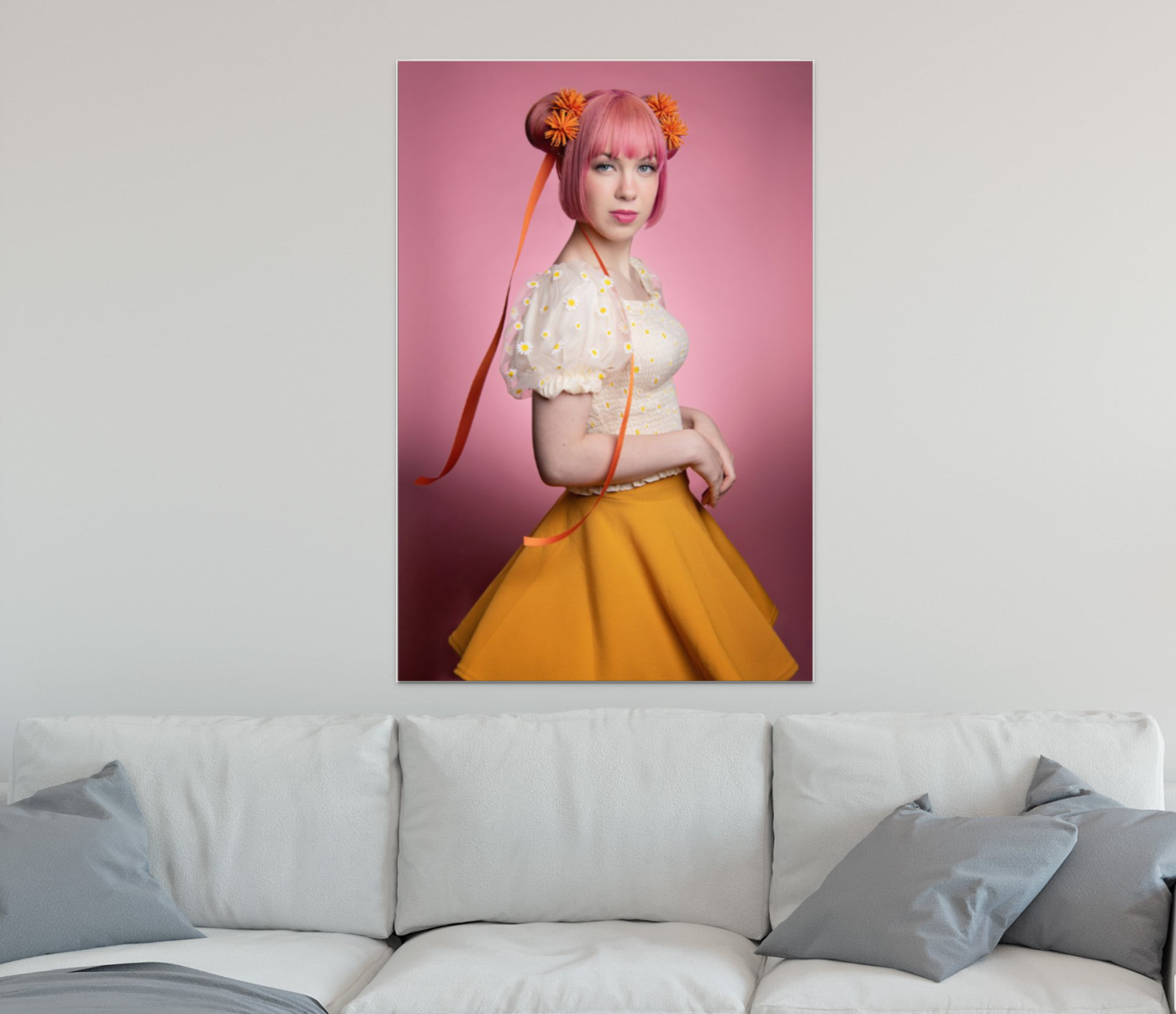 A wall art print mounted above a gray couch shows an anime styled portrait in yellow and pink tones.