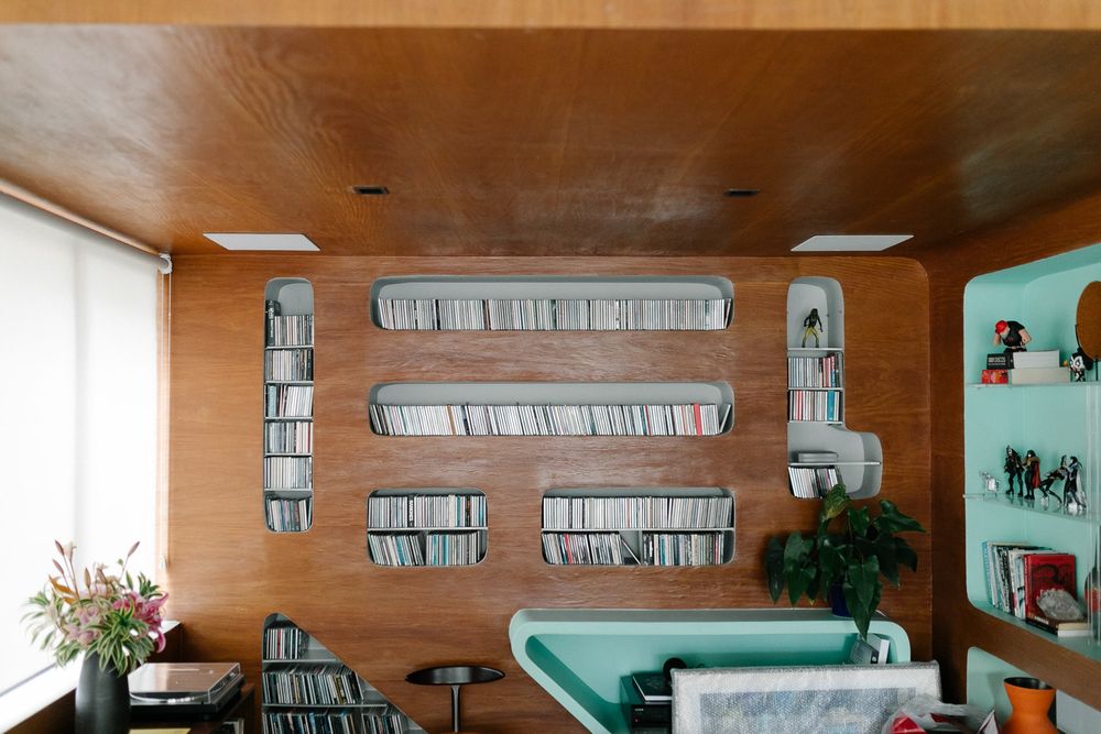 Mid-century modern room with wood paneling and built-in shelving displaying records.