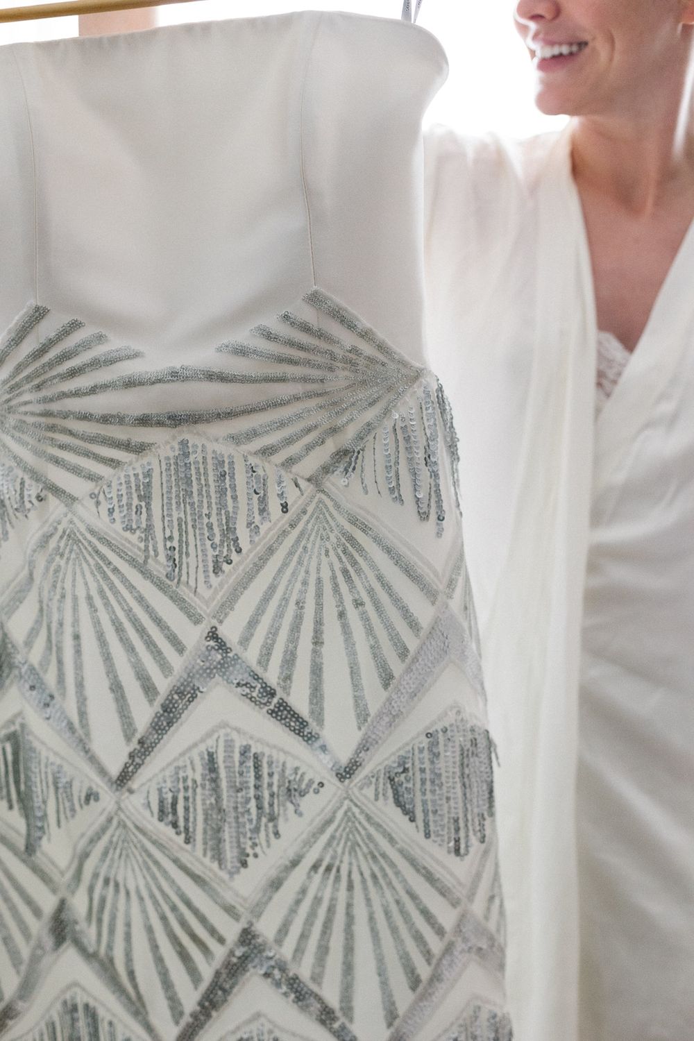 Detail shot of an art deco inspired beaded pattern on a white dress.