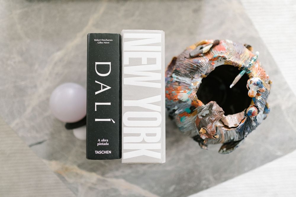 Book and decorative ceramic object arranged on marble surface.