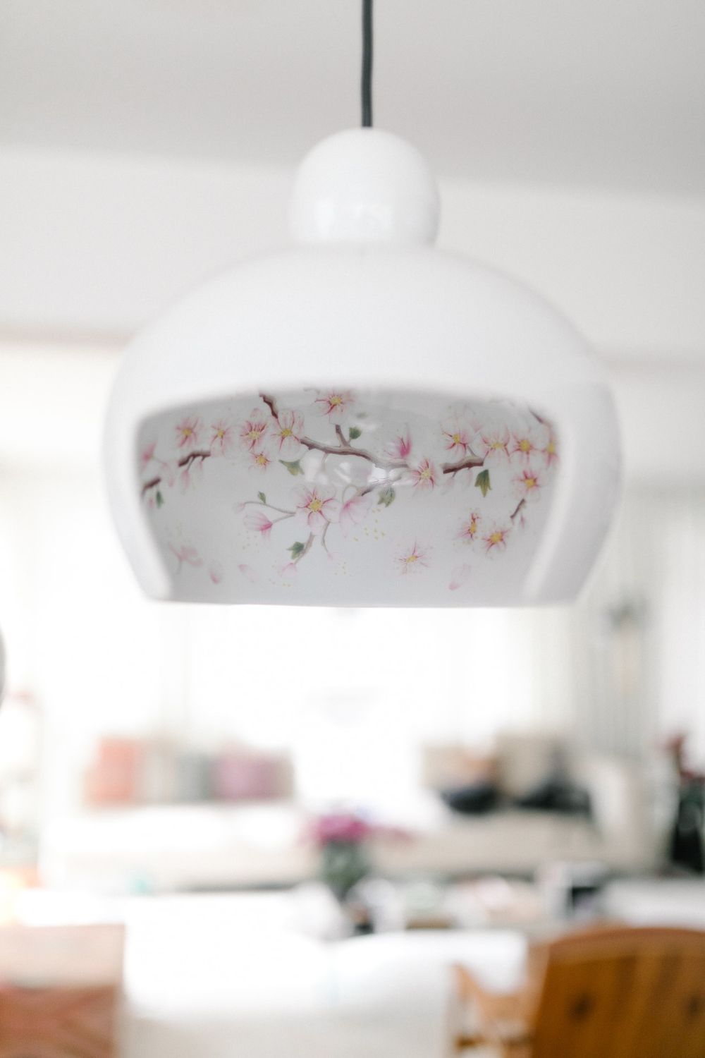 White pendant lamp with delicate floral pattern detail hanging from ceiling.