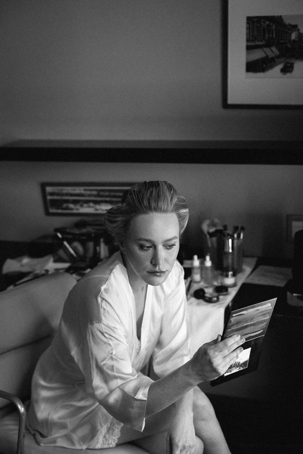 Black and white portrait of person in white robe looking at phone.